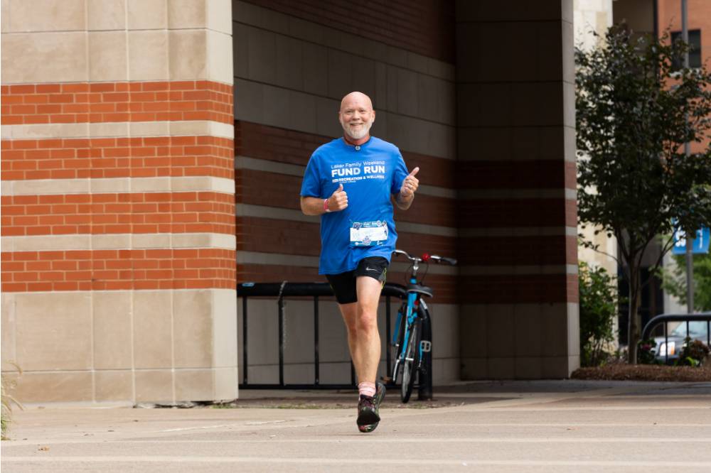 Participant nearing finish line holding thumbs up